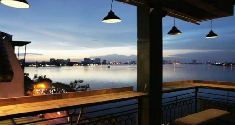 Dãy bàn ngoài ban công tầng 4 với view nhìn thẳng ra Hồ Tây dưới ánh đèn vàng lung linh